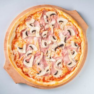 a pizza with mushrooms and ham on a wooden board